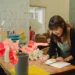Pessoa anotando um pedido de encomenda em um caderno, com flores ao lado, em ambiente de loja