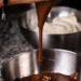 Chocolate derretido sendo despejado em tigela, superfície brilhante (imagem ilustrativa)