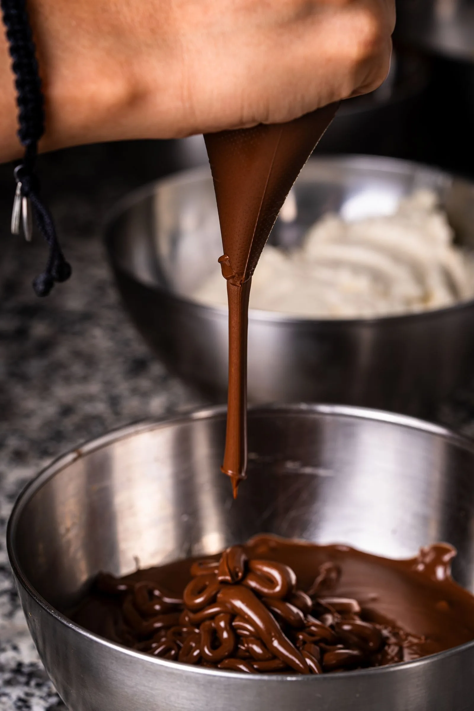 Chocolate derretido sendo despejado em tigela, superfície brilhante (imagem ilustrativa)