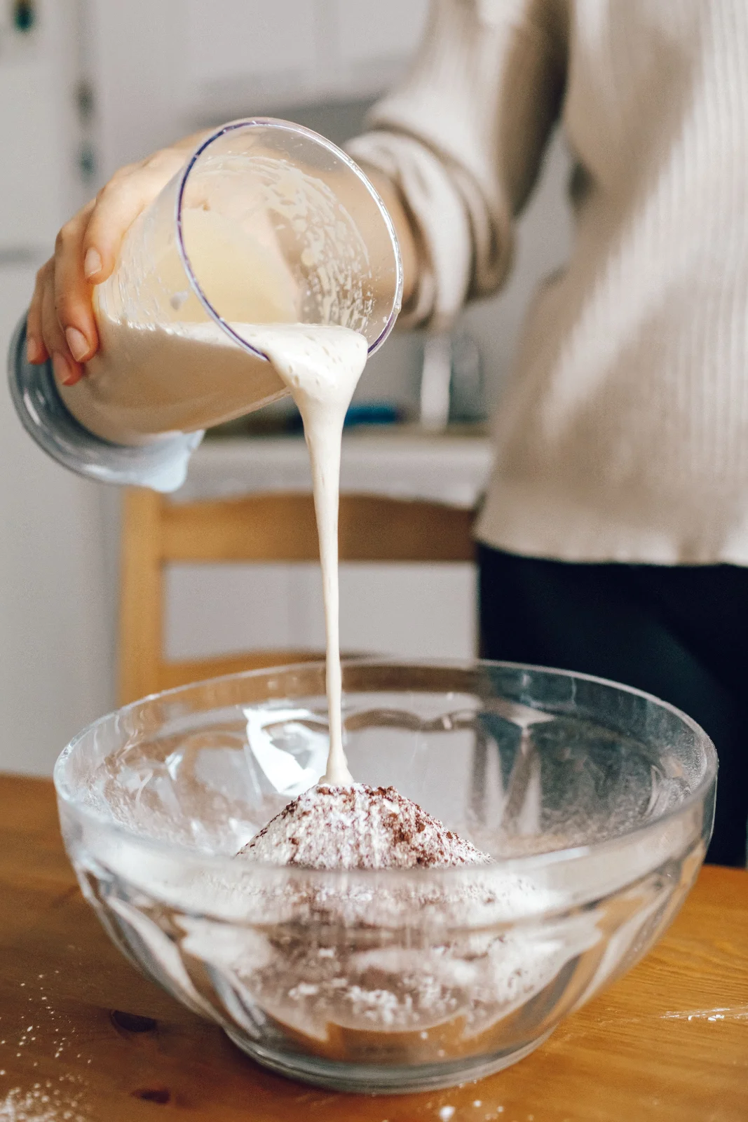 Creme de leite sendo despejado de um recipiente durante o preparo do brigadeiro
