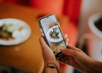 Pessoa fotografando um prato de doce com o celular para publicar em rede social