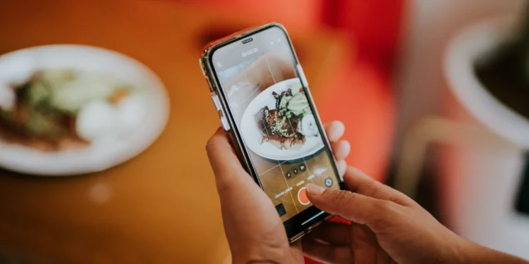 Pessoa fotografando um prato de doce com o celular para publicar em rede social