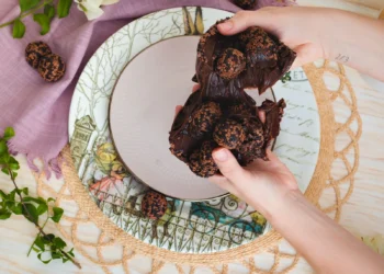 Mãos segurando docinhos de chocolate enrolados (imagem ilustrativa)