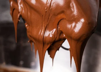 Massa de chocolate brilhante escorrendo em batedor de arame (imagem ilustrativa)