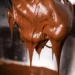 Massa de chocolate brilhante escorrendo em batedor de arame (imagem ilustrativa)