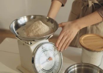 Pessoa pesando um ingrediente em uma balança de cozinha digital
