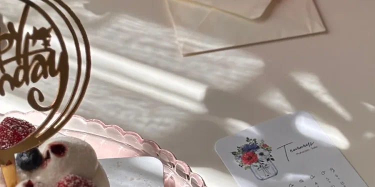 Mesa com bolo de comemoração, convite e itens de planejamento de festa