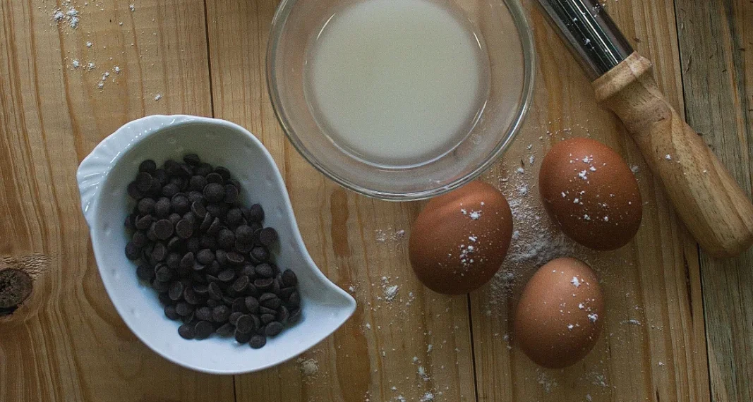Utensílios de cozinha e ingredientes organizados sobre uma mesa de madeira, usados no preparo de doces