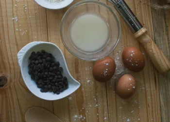 Utensílios de cozinha e ingredientes organizados sobre uma mesa de madeira, usados no preparo de doces