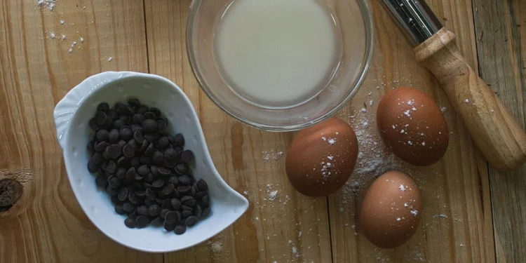 Utensílios de cozinha e ingredientes organizados sobre uma mesa de madeira, usados no preparo de doces